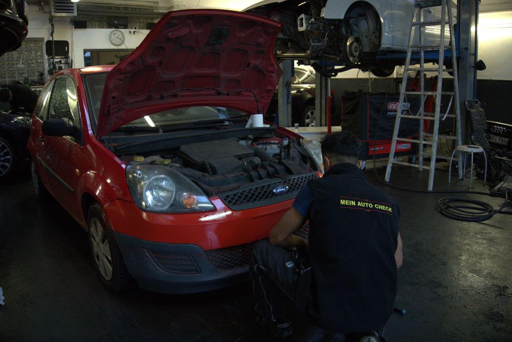 Mechaniker arbeitet an einem Fahrzeug in der Werkstatt von Mein Auto Check
